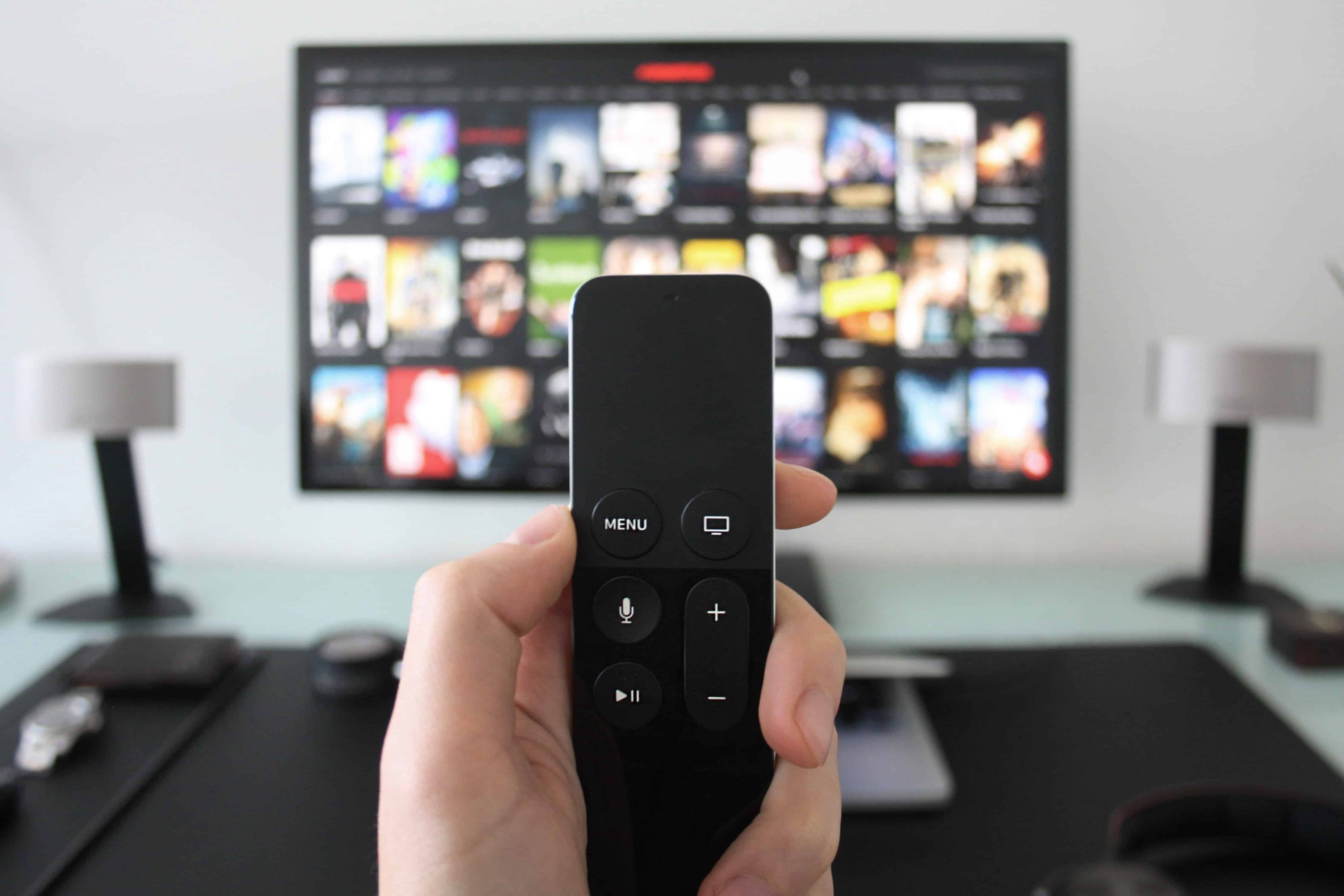hand holding a remote control in front of tv screen